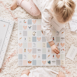 Child playing with educational game board on a soft rug.