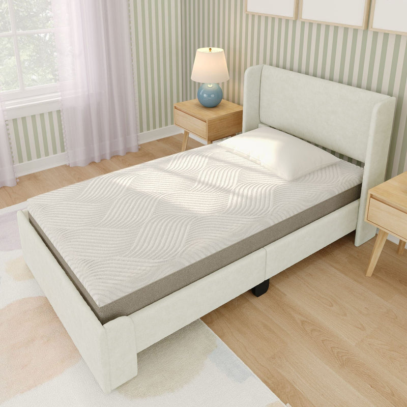 White upholstered twin bed with textured mattress, wooden nightstands and blue lamp in bright minimalist bedroom with green striped wallpaper