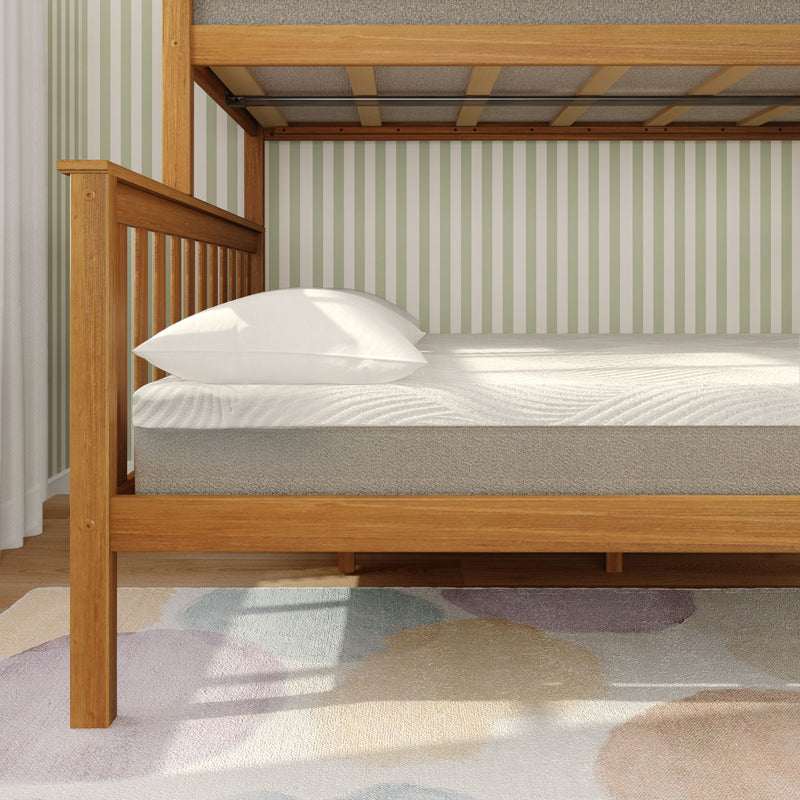 Natural wood bunk bed with white pillow on twin mattress in a child's room with green striped wallpaper and pastel abstract rug