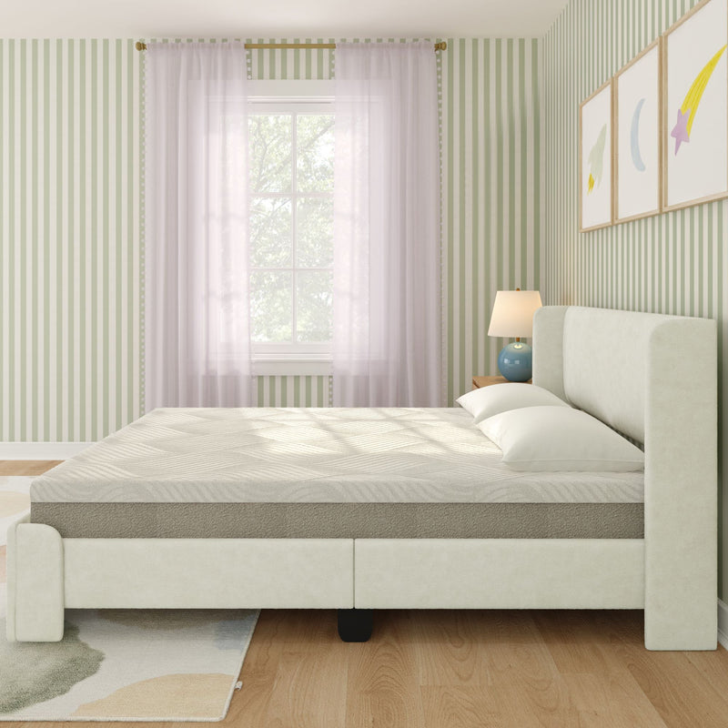 Minimal modern upholstered bed with neutral mattress in a sunlit bedroom featuring green striped wallpaper, sheer curtains, wooden nightstand and lamp