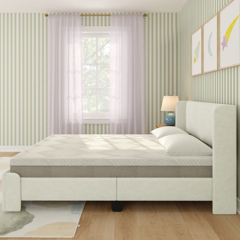 Minimal modern upholstered bed with neutral mattress in a sunlit bedroom featuring green striped wallpaper, sheer curtains, wooden nightstand and lamp