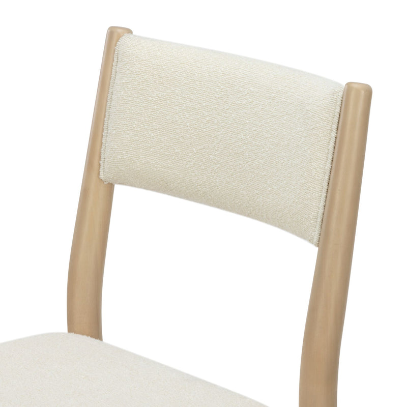 Close-up of cream bouclé upholstered dining chair backrest with light natural wood frame, modern minimalist design