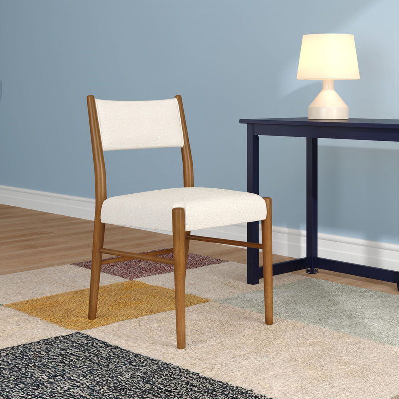 Mid-century modern wooden dining chair with cream upholstery next to navy side table, white table lamp and multicolor area rug against a blue wall