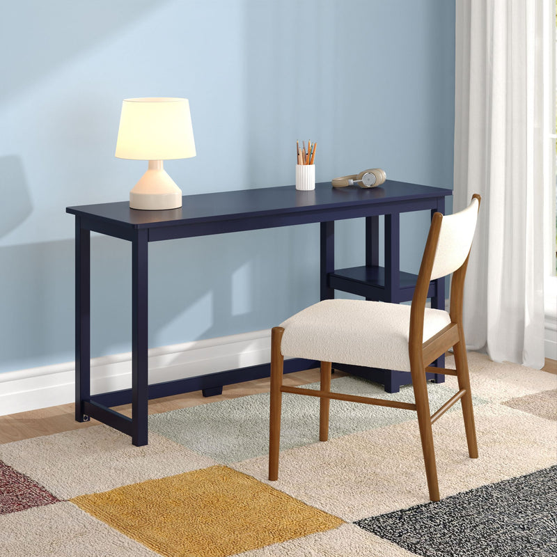 Modern home office desk with white lamp, pencil holder and headphones on navy desk against a light blue wall