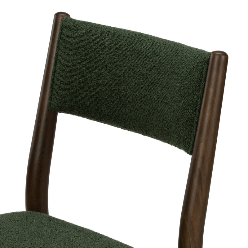 Close-up of green boucle upholstered dining chair back with dark walnut wood frame, textured mid-century modern seating detail