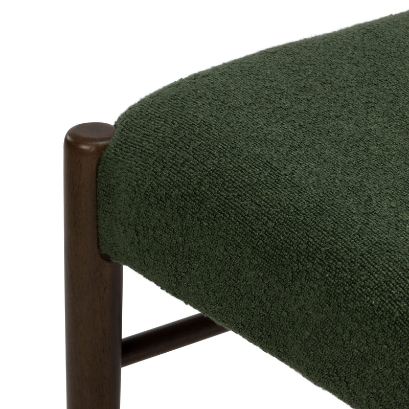 Green bouclé upholstered chair close-up showing textured forest-green fabric seat and dark walnut wood frame detail