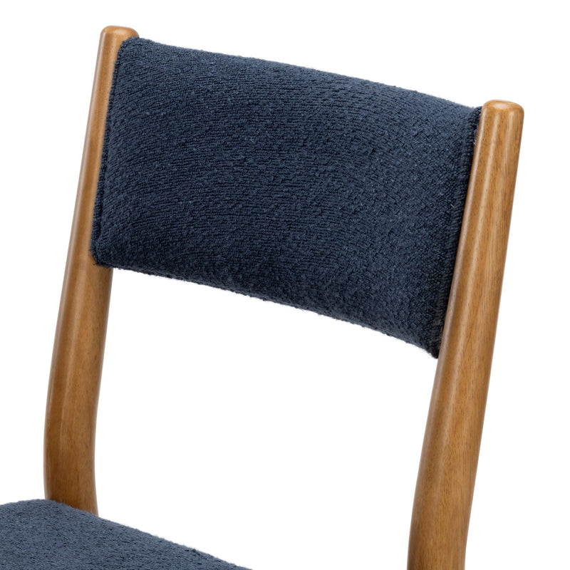 Close-up of navy textured upholstered chair back with curved walnut wood frame, mid-century modern dining chair detail