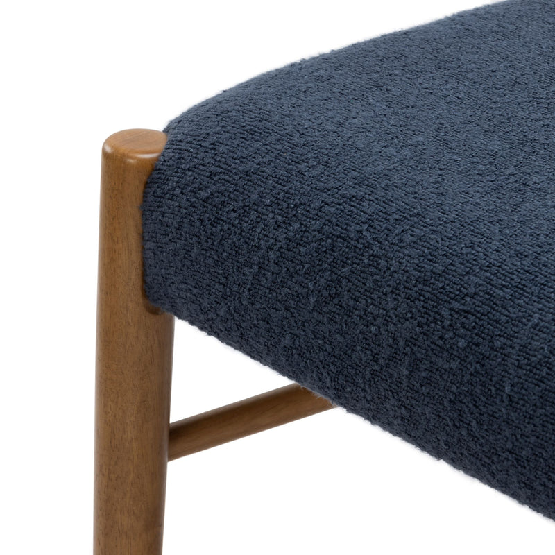 Close-up of navy blue textured boucle upholstery on an upholstered seat with smooth wooden stool leg