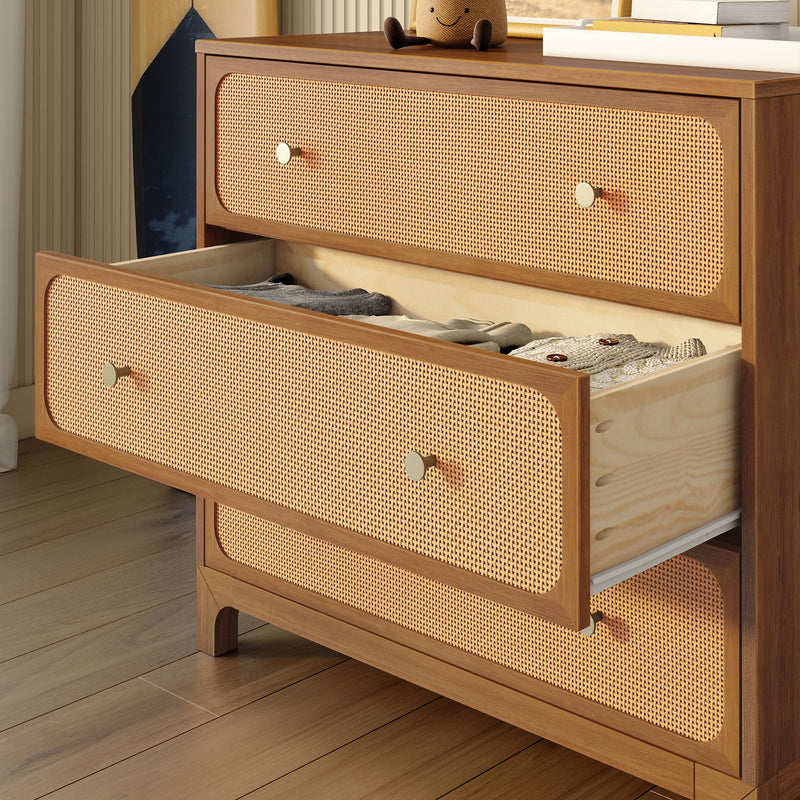 Mid-century modern walnut dresser with woven rattan (cane) drawer fronts and brass knobs, open drawer revealing neatly folded knit clothes on hardwood floor