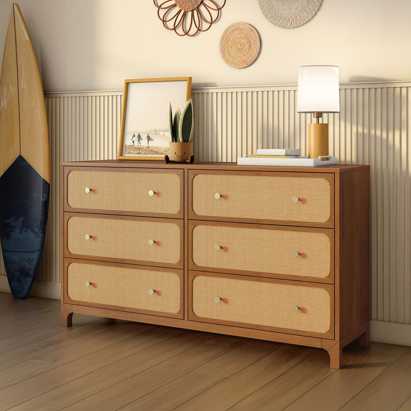 Mid-century modern wooden six-drawer dresser with woven rattan fronts, lamp, potted plant, framed beach photo and surfboard