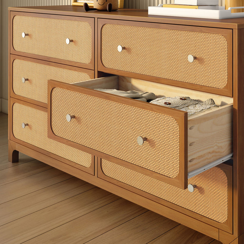 Mid-century modern warm wood dresser with six natural rattan cane drawer fronts, one open drawer showing folded knitwear — bedroom storage