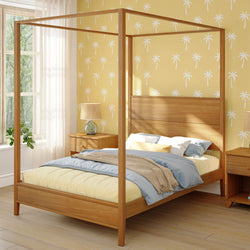 Four-poster bed in a stylish bedroom with tropical-themed wallpaper and natural light.