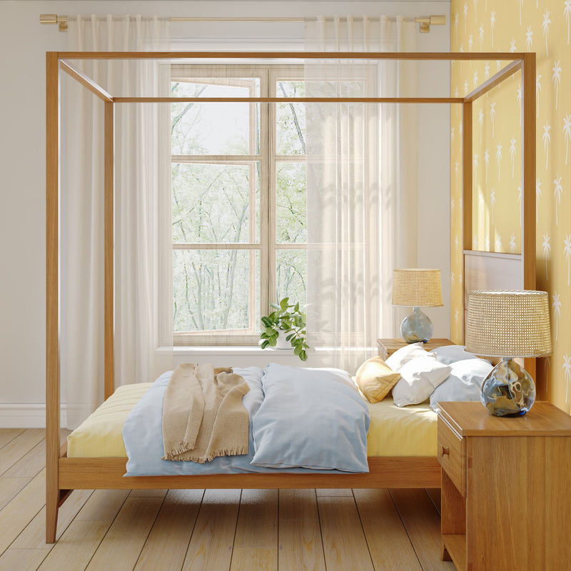 Cozy bedroom with a wooden canopy bed, blue and yellow bedding, and natural light from a large window.