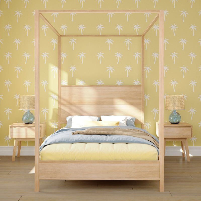 Modern coastal bedroom with light wood canopy bed, yellow palm-print wallpaper, rattan bedside lamps and pastel blue and yellow bedding