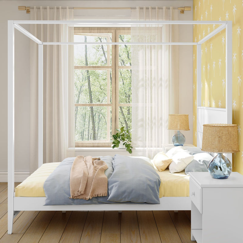 Bright coastal bedroom interior with white canopy bed, pastel blue pillows, yellow palm‑print accent wall, sheer curtains and rattan lamps