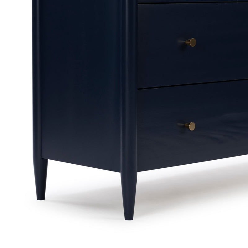Close-up of navy blue wooden nightstand with tapered legs and brass round drawer knobs, mid-century modern bedside table