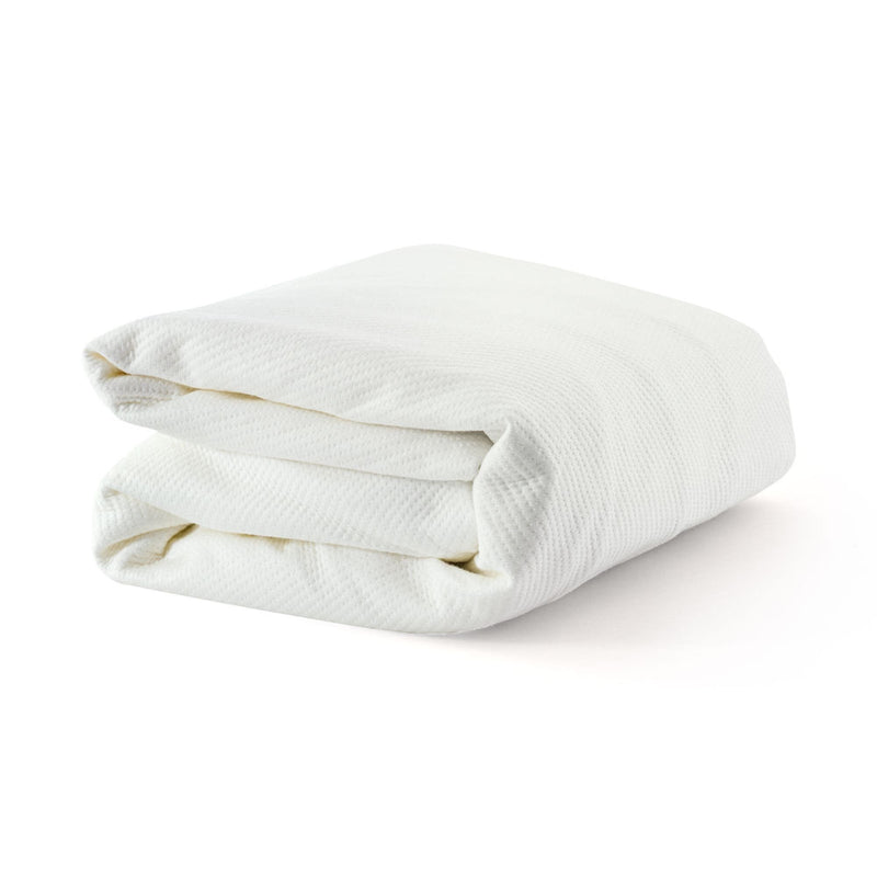 Folded white waffle-textured cotton blanket on white background, soft breathable bed throw for bedroom