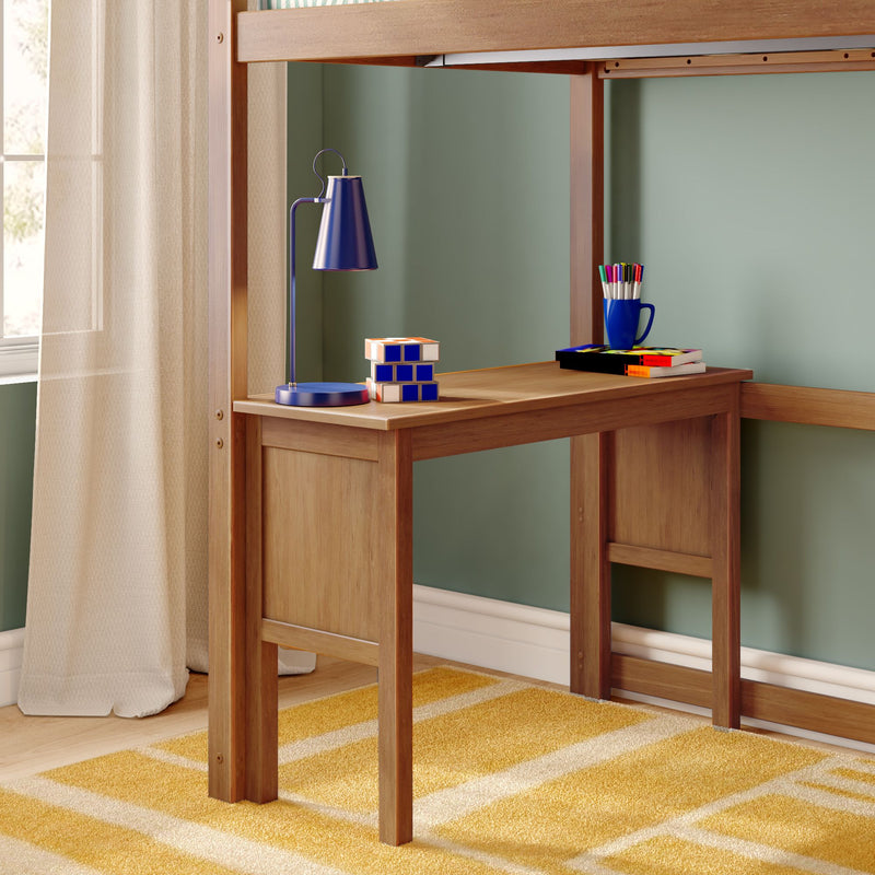 Wooden loft bed with built-in study desk, blue desk lamp, puzzle cube and marker cup on a natural wood workspace in a kids' bedroom with green wall and yellow striped rug