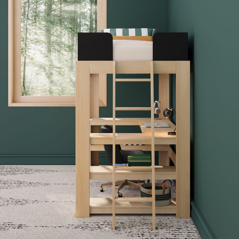 Natural wood loft bed with built-in desk and ladder in a green bedroom, striped pillow on mattress, desk lamp and chair below, storage basket and books, large window with forest view