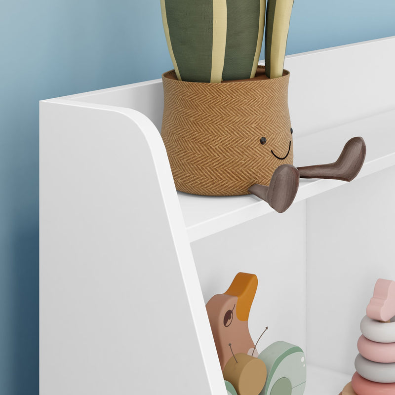 White leaning children's shelf in nursery displaying pastel wooden stacking rings, pull duck toy, and smiling woven plant pot with cactus — playroom decor and storage