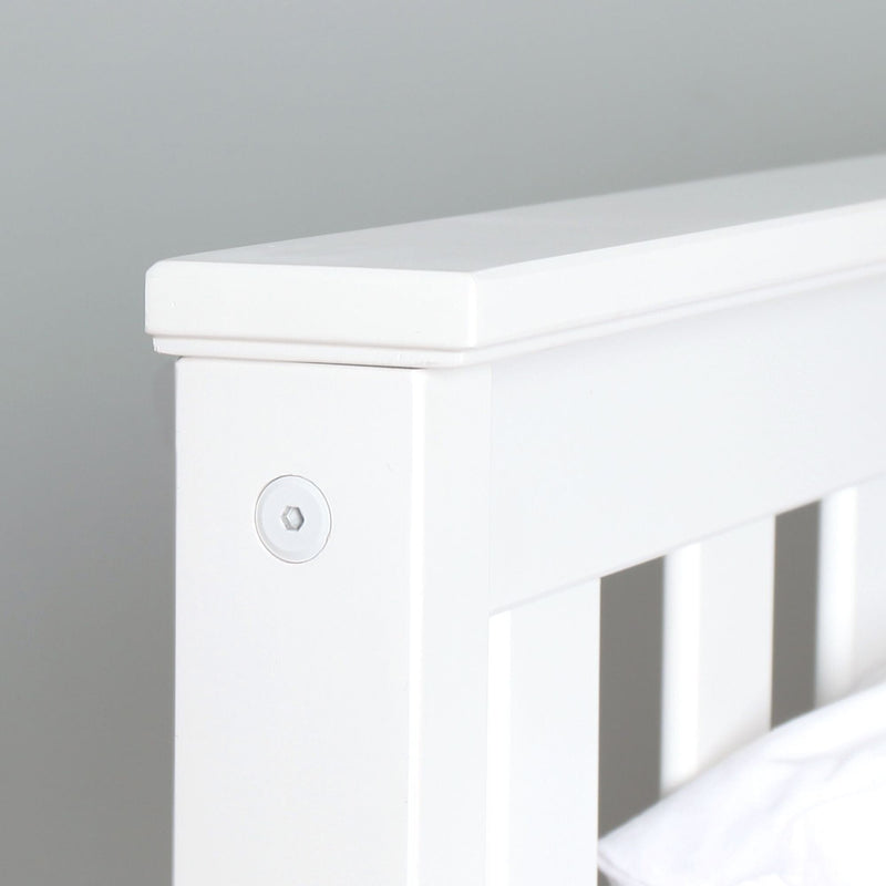 Close-up of white painted wooden slatted bed headboard corner with recessed hex bolt, modern farmhouse bedroom furniture