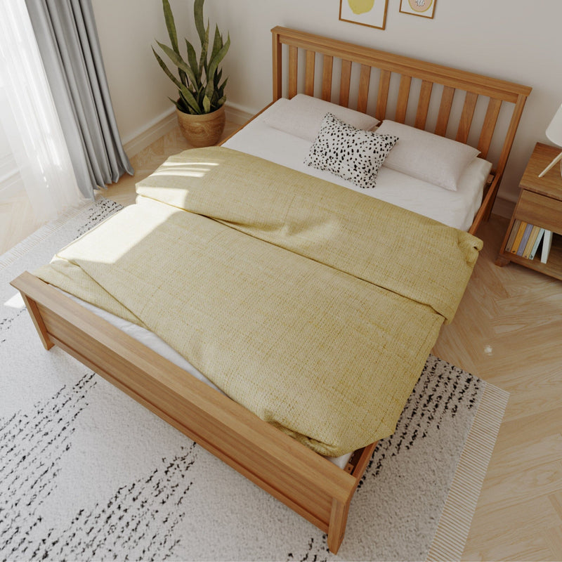 Scandinavian bedroom with wooden slatted bed frame, yellow duvet, black-and-white accent pillow, potted snake plant, bedside table and soft natural light