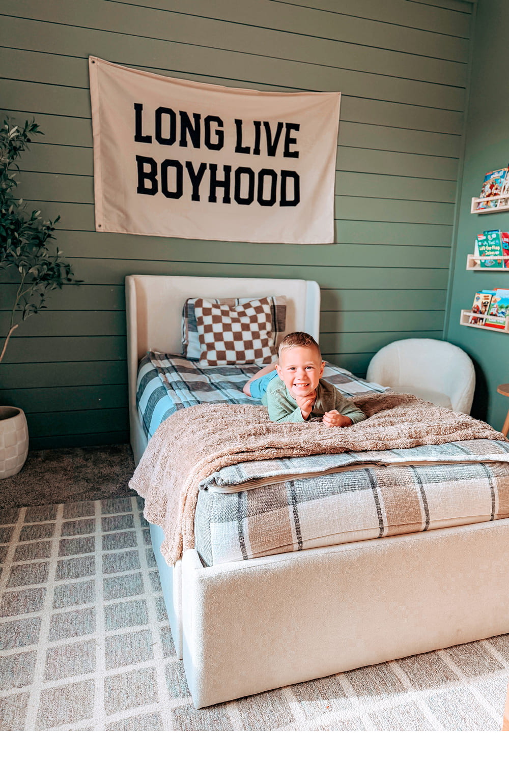 little boy laying on a single, upholstered bed