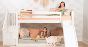 White low bunk bed with slide and stairs in shared girls room