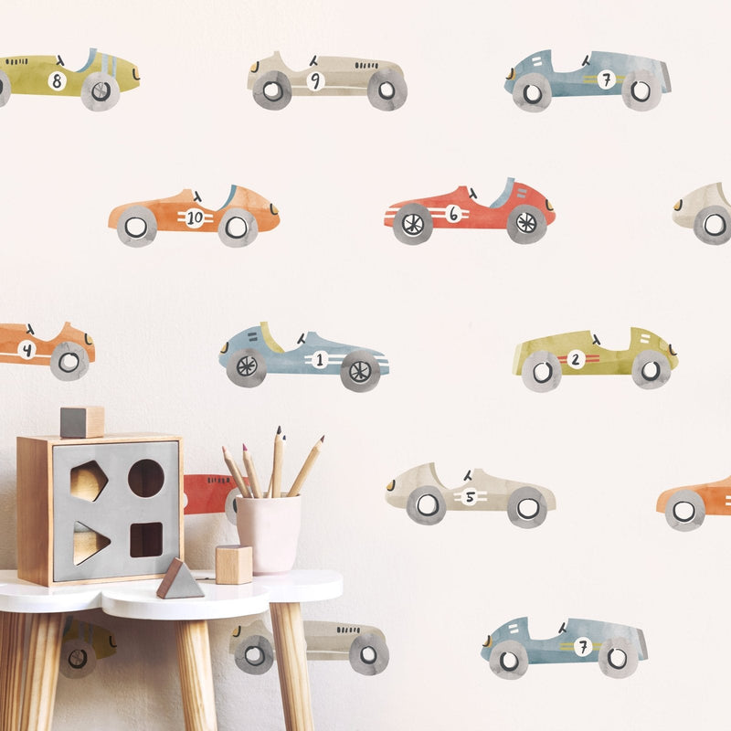 Nursery with pastel vintage race car wall decals, wooden shape sorter toy and pencils on a white stool — kids room decor