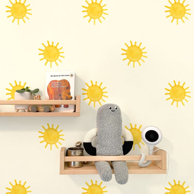 Nursery decor with yellow sun wall decals, light wood floating shelves holding a potted plant, wooden toy car, 