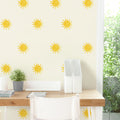 Bright desk workspace with yellow sun-pattern wallpaper, white desk organizers, potted plant and natural light
