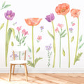 Watercolor floral wall decal mural featuring orange poppies, purple tulips and pastel wildflowers over a white chair on hardwood floor — removable nursery wall art and vinyl sticker décor for bedroom or living room