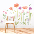 White wooden chair on light hardwood floor in front of watercolor floral wall decals featuring orange poppies and purple tulips