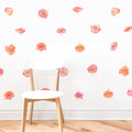 White modern wooden chair against a white wall with scattered pink and coral poppy removable floral wall decals on a hardwood floor, minimalist nursery or bedroom decor