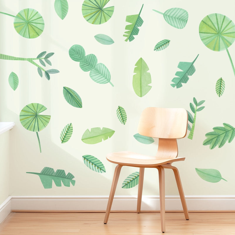 Wooden chair beside green watercolor leaf wall mural on cream wall — botanical wall decals for modern interior decor