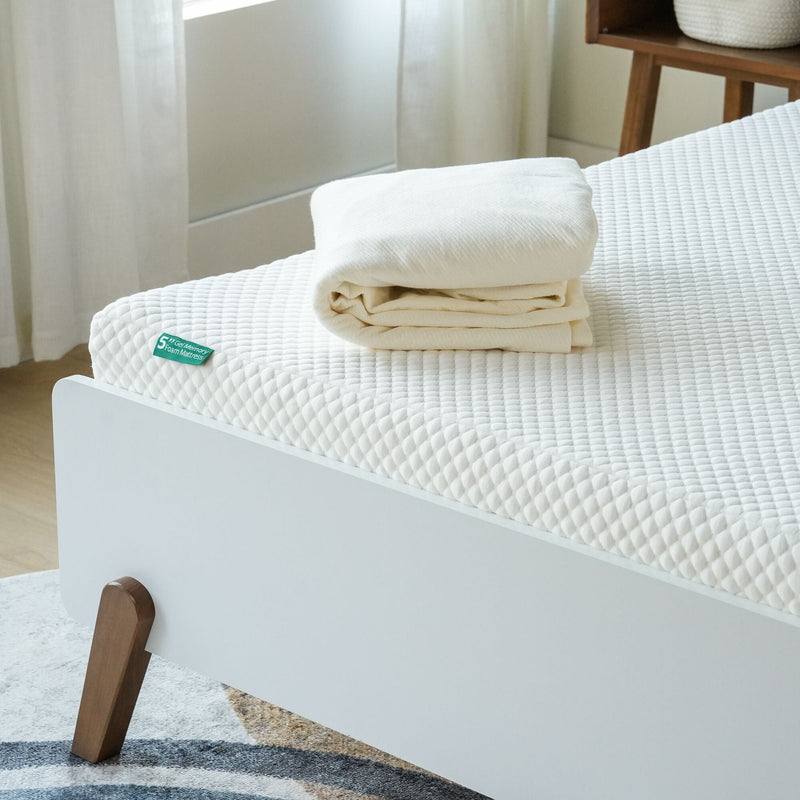 Memory foam mattress with folded bedding on a modern bed frame