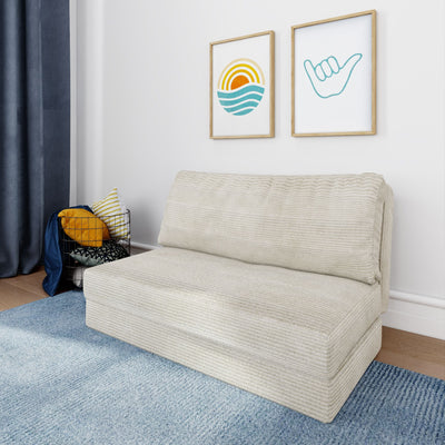 Minimalist living room with beige textured sofa, blue area rug, navy curtains, coastal sun and shaka framed wall art, and wire basket of yellow striped throw pillows.