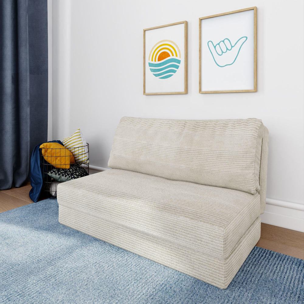 Cream-colored foldable sofa in modern living room with blue rug and wall art, perfect for small spaces.