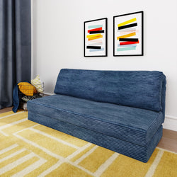 Modern living room with a blue corduroy sofa, abstract art on the wall, and a yellow geometric rug.