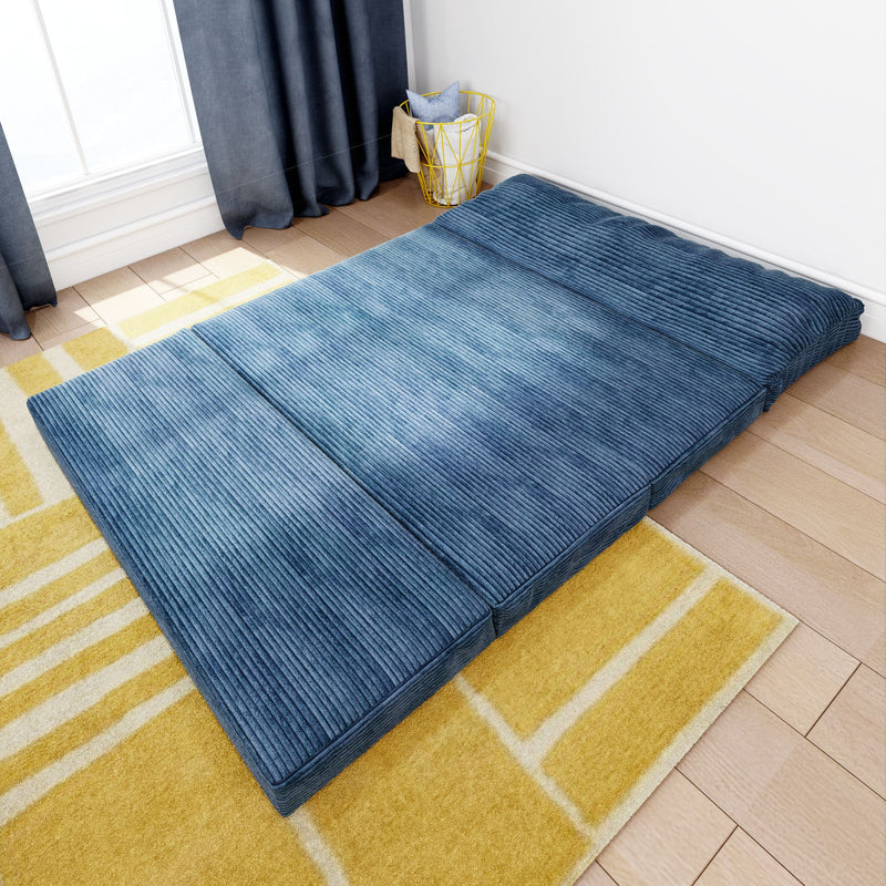 Blue foldable futon mattress on a wooden floor next to a yellow patterned rug, perfect for small spaces and modern living room decor.