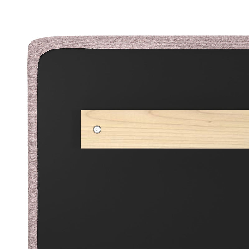 Back view of pink upholstered headboard with black backing and horizontal wooden mounting bracket secured by screw for wall-mount installation, bedroom headboard hardware detail