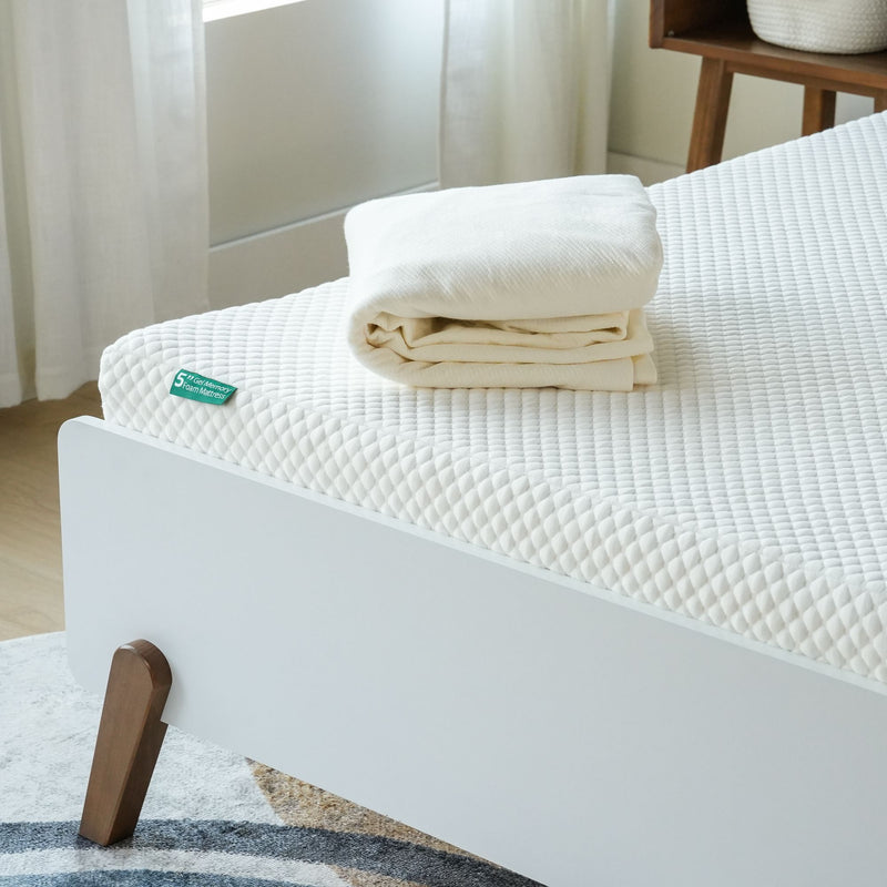 Memory foam mattress with soft textured surface and folded white linens.
