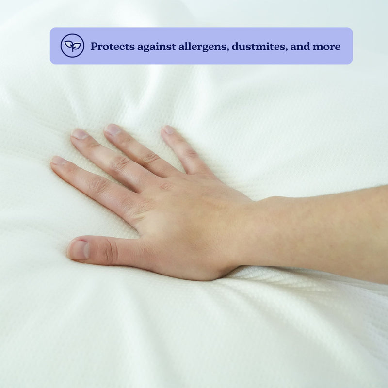 Hand pressing down on a white hypoallergenic mattress protector, emphasizing its protection against allergens and dust mites.