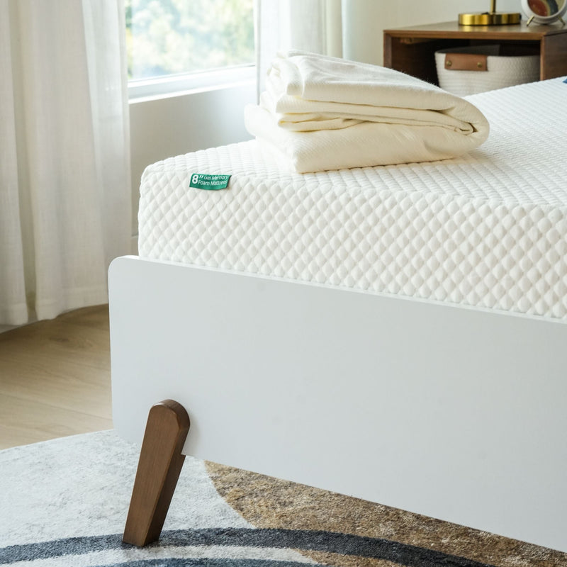 Memory foam mattress with white bedding in modern bedroom setting.
