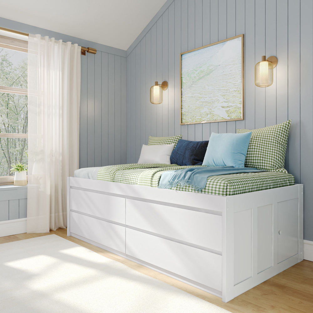 Cozy bedroom with daybed featuring blue and green plaid bedding, white storage drawers, light blue walls, and natural light from a large window.