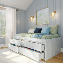 Cozy small bedroom with a daybed featuring storage drawers, accent pillows, and blue wall paneling, perfect for optimizing small space design.