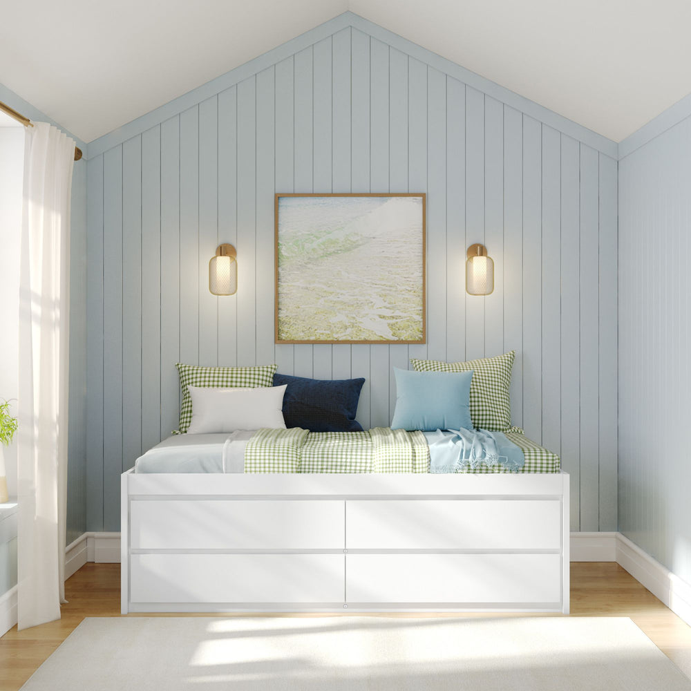 Modern cozy bedroom with white daybed, blue and green pillows, light blue paneled wall, and wall sconces.