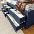 Blue wooden bed with built-in under-bed storage drawers filled with neatly folded linens and plaid bedding on hardwood floor