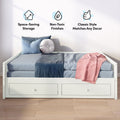 White wooden daybed with two under-bed storage drawers, blue bedding, pink throw and round pillow on hardwood floor, product image highlighting space-saving storage, non-toxic finishes and classic style