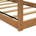 Close-up of oak wooden platform bed frame corner with natural finish, evenly spaced wood slats, black center support straps and sturdy corner post with hex bolts